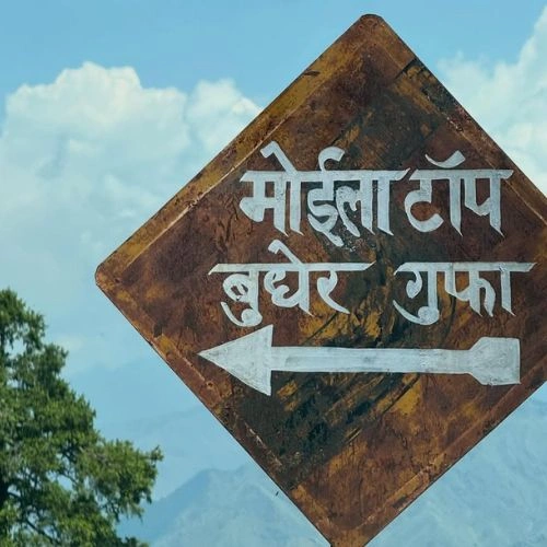 Budher Cave in Chakrata surrounded by dense forest with trekkers exploring the natural cave