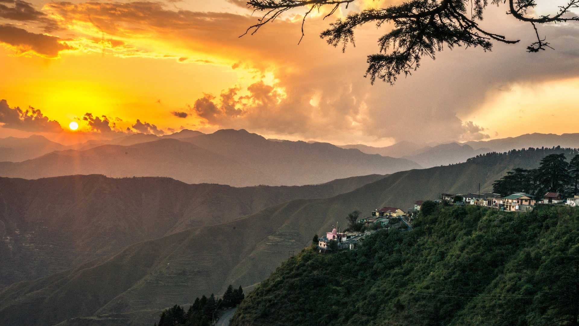 Sunrise view over Chakrata hills with golden sunlight illuminating lush green valleys and Himalayan peaks