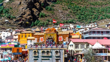 Badrinath Temple surrounded by Garhwal Himalayas with devotees and clear blue sky