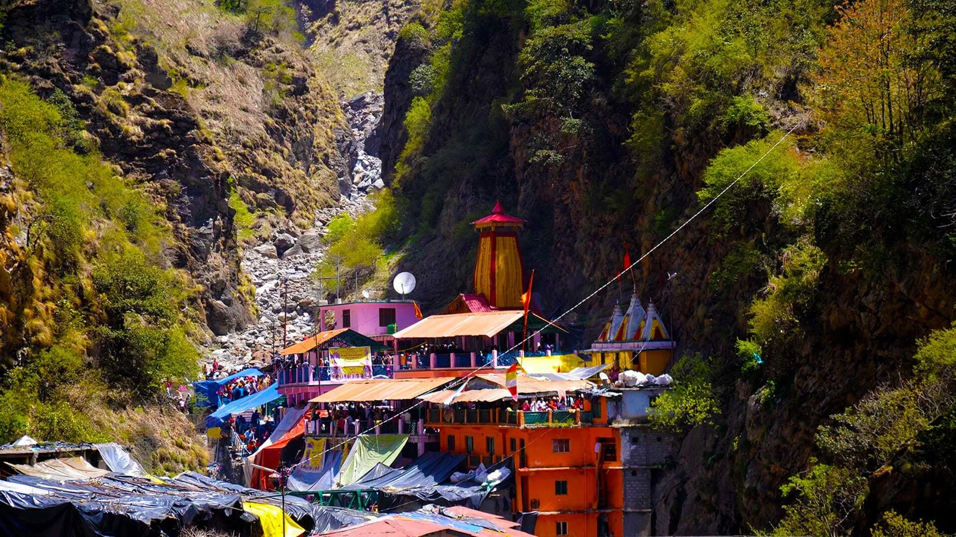 Pilgrims visiting Yamunotri Temple with Himalayan backdrop and clear blue sky