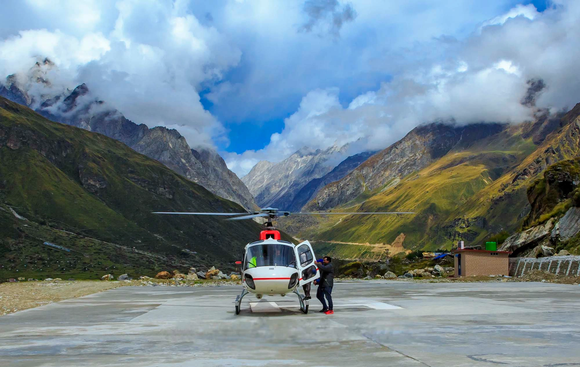 Kedarnath Helicopter service flying over Himalayan mountains with Kedarnath Temple view and pilgrims