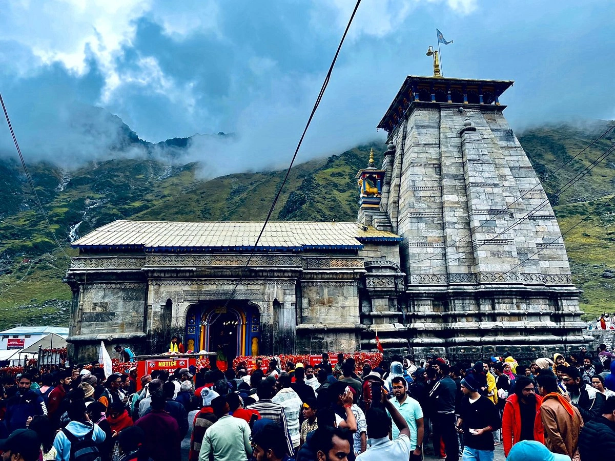Pilgrims visiting Kedarnath Temple with Himalayan backdrop and clear blue sky