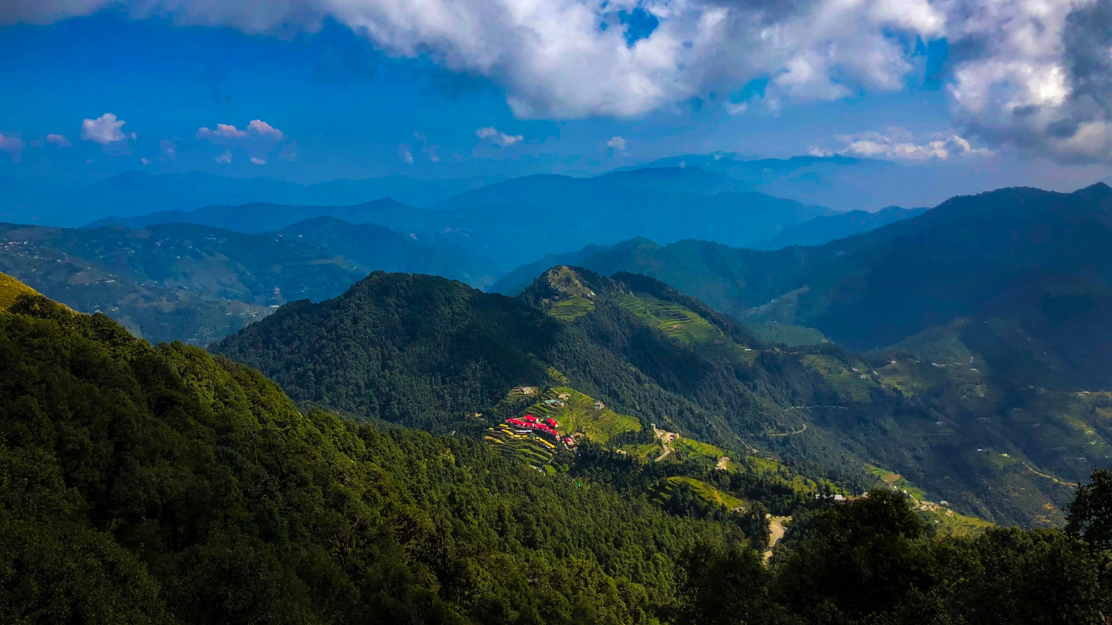 Aerial view of Kanatal hills showing rolling mountains, lush greenery, and peaceful valley